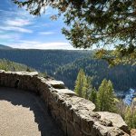 Man overlooking a canyon while sitting on a rock wall